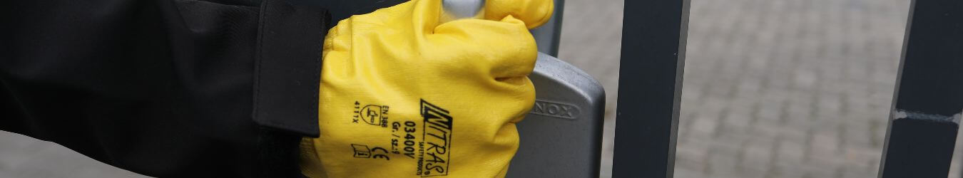 Gelber Baumwollhandschuh von Alpha-Tex Gelber Baumwollhandschuh hält einen Griff in der Hand